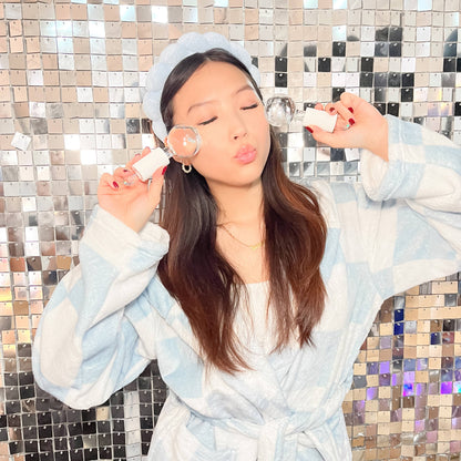 Close-up of a woman using ESW Beauty Pink Glitter Ice Globes for a cooling under-eye facial treatment